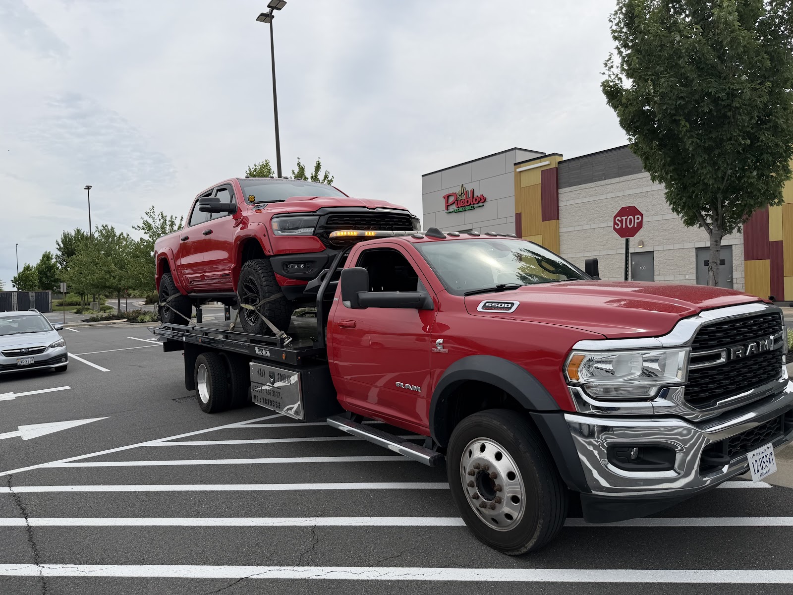 Navy Towing's red flatbed truck carrying a red pickup