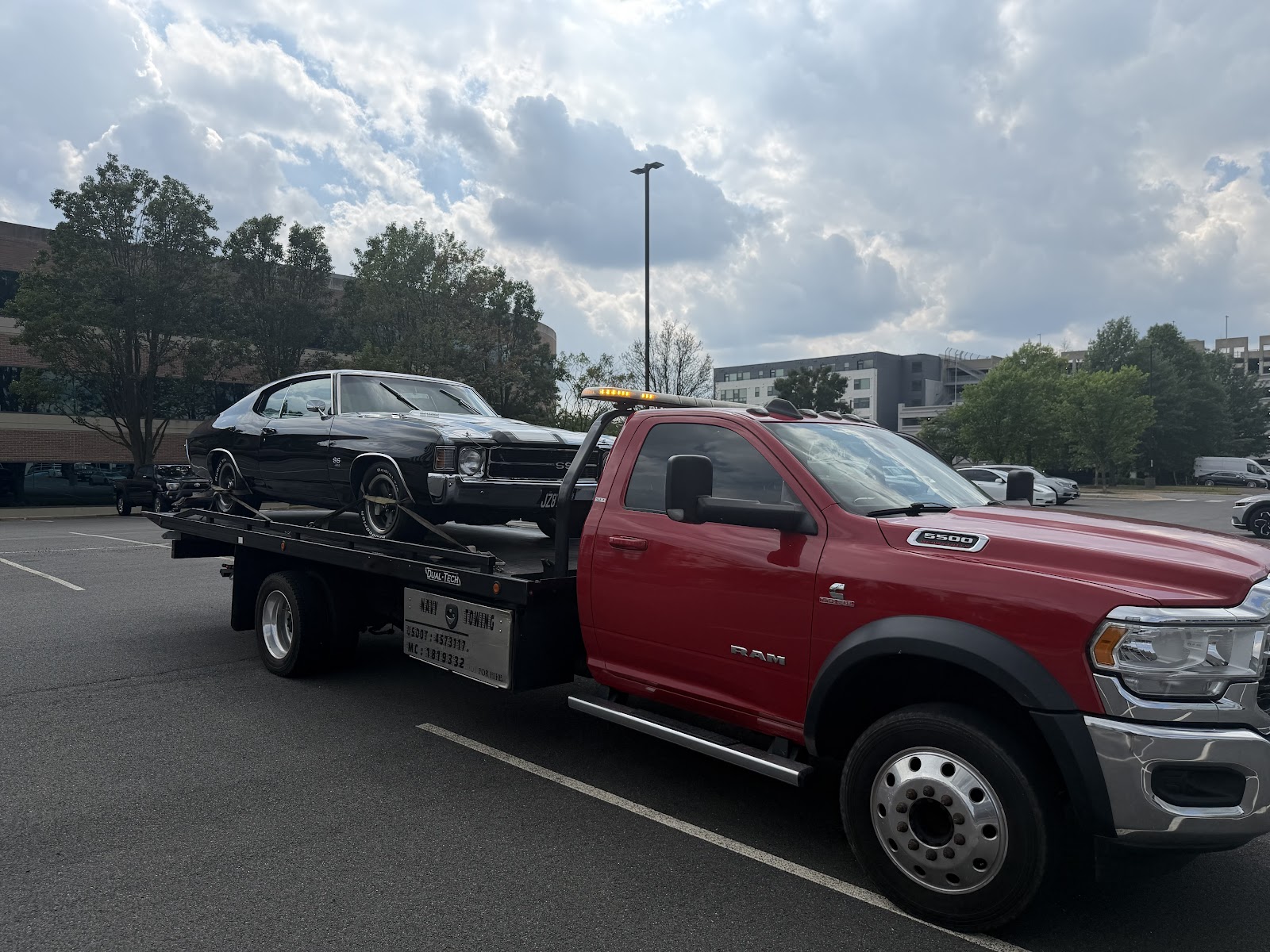 A black vehicle on Navy Towing's red flatbed truck